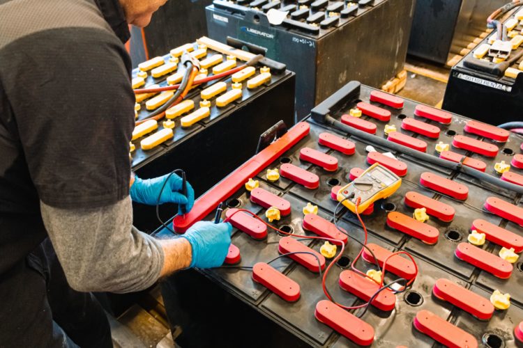 A technician performing maintenance on a forklift battery