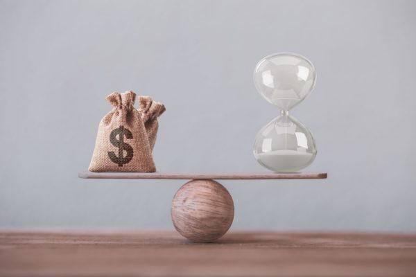 A money bag balancing against an hourglass