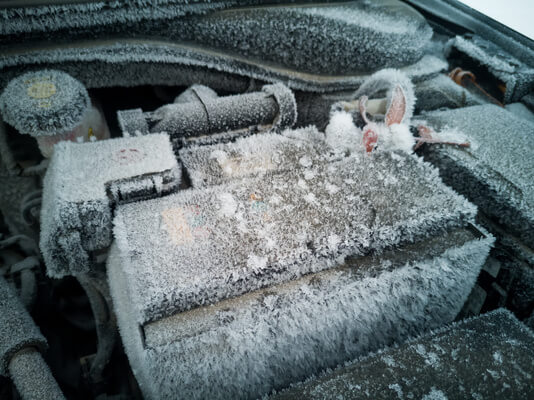 A frozen car battery in an engine compartment