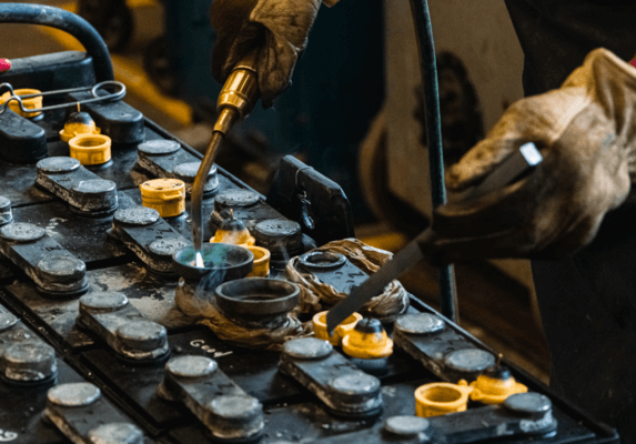 A battery technician heating the inside of a battery cell with a torch