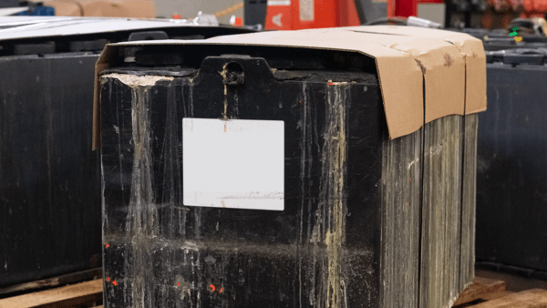 A spent forklift battery banded to a skid for disposal