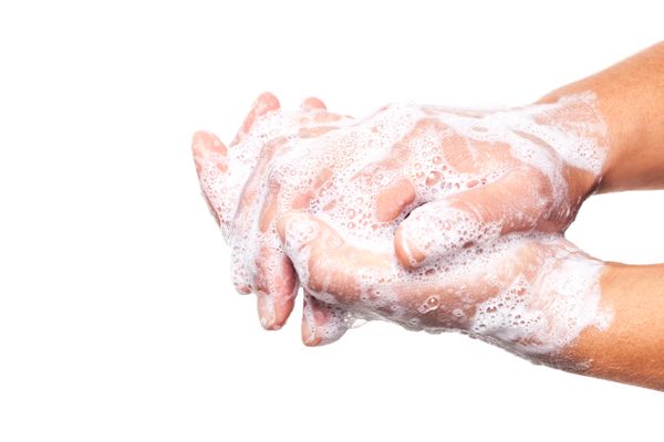 A person washing their hands with soap in a sink